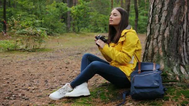 Jovem mulher incrível sentado na árvore e tirar fotos da natureza na câmera vintage na floresta verde. Ao ar livre — Vídeo de Stock