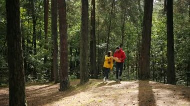 Genç turist çift renkli kat olarak ve ormanda geziniyor ve harita üzerinde seyir sırt çantaları ile. Açık havada