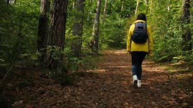 Arkadan görünüm genç sportif kadın turist vintage kamera güzel yeşil ormanda yalnız dolaşım ve kamera için geri dönüyor. Açık havada