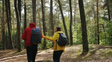 Arka turistler güzel ormanın ortasında hiking renkli kat ve sırt çantaları ile genç çiftin. Dışarıda