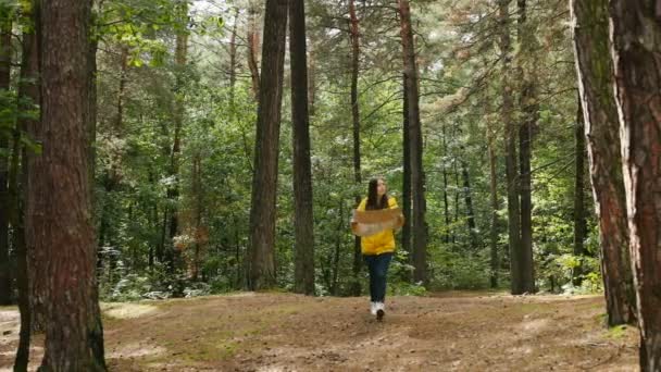 Belle randonneuse en manteau jaune marchant seule dans la forêt et tenant la carte dans ses mains. À l'extérieur — Video