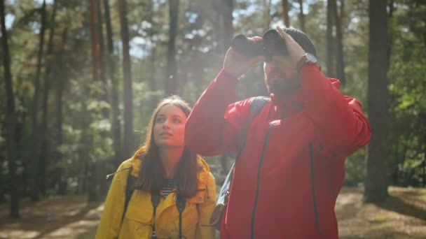 Jeune couple heureux s'amusant dans la forêt. Femme tachant des photos de la nature sur l'appareil photo vintage et homme regardant dans les jumelles. À l'extérieur — Video