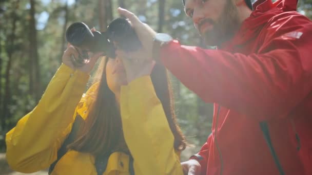 Portrait de l'homme beau donnant des jumelles à sa petite amie pour regarder la nature dans la forêt. Ferme là. Extérieur — Video