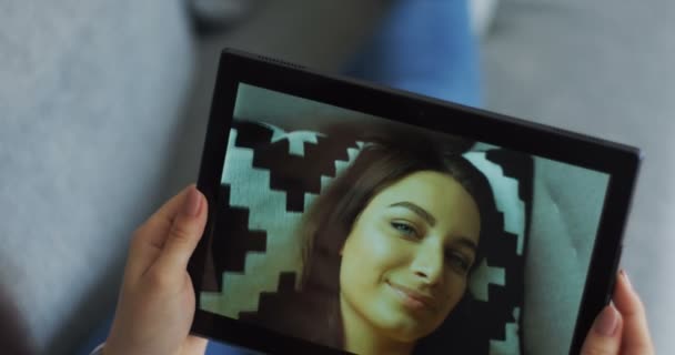 Черный планшетный компьютер с привлекательной женщиной с веб-камерой на экране. Крупный план женских рук, держащих устройство . — стоковое видео