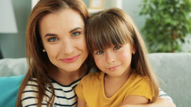 彼女の膝と笑顔のかわいい小さな娘を保持している美しい母親の肖像画 クローズ アップ — ストック動画