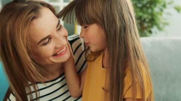 Niedliche hübsche Mutter und Tochter umarmen, streicheln und lachen im gemütlichen Zimmer. Nahaufnahme. Porträt. Innenräume — Stockvideo