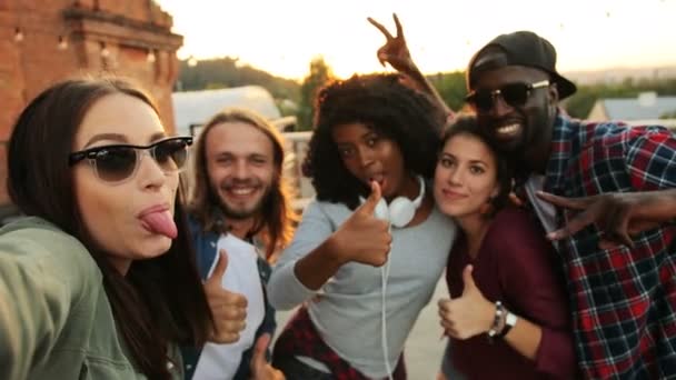 Przyjaciele mieszanej rasy podejmowania selfie i wysyłanie pocałunki z kamerą na imprezie na dachu. Miejskich. Tło zachód słońca. Na zewnątrz. — Wideo stockowe