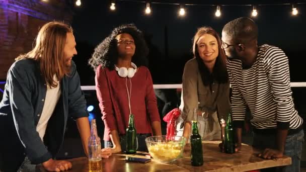 Portrait of mixed-raced young people standing around the table at the rooftop party at night. The brick wall background. Outdoors — Stock Video