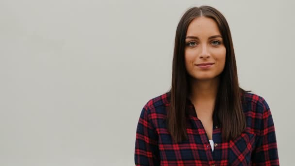 Retrato de una hermosa mujer joven con camisa a cuadros de pie sobre fondo blanco. Una chica con estilo. Al aire libre . — Vídeos de Stock