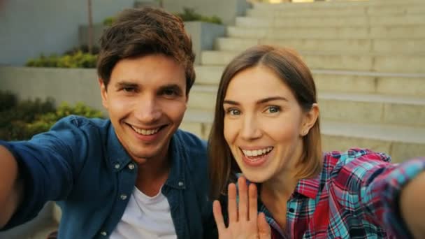 Sorrindo jovem casal caucasiano ter vídeo chat com as escadas no fundo, compartilhando memórias de verão com seus amigos. Fechar . — Vídeo de Stock