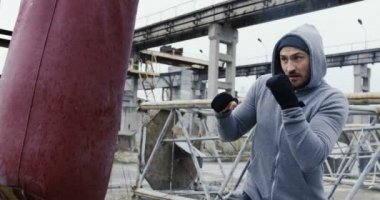 Kötü gri havada atılmış eski fabrika alanında Kırmızı çantalı beyaz çekici sporcu bir gri kapşonlu eğitim kutusunu. Açık