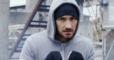 Bir kap içinde genç adam kadar yakın ve hood boks eski bitki üzerinde kamera önünde arka mahvediyor. Soğuk gri gün. Portre vurdu. Açık