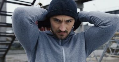 Bir kaputa alarak ve tekmelemek kızgın kameraya başlayan yakışıklı genç boksör. Fabrika bölge gri soğuk sabah atılmış. Yakın çekim. Portre vurdu