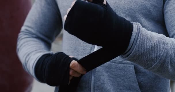 Крупним планом привабливий молодий чоловік боксер, обмотаний руками чорною тканиною за межами заводу руїни в сірий день в тумані. Портрет — стокове відео