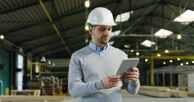 Onun elinde bir tablet ile yürüme ve etrafa beyaz erkek bitki işçi. Bir werehouse planlama. Kapalı. Portre