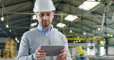 Kayıt ve onun tablet cihaza ve büyük fabrikada Oda kameraya bakarak daha kaydırma bir kask içinde çekici mühendisi kapatın. Kapalı. Portre