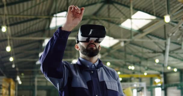 Ingeniero masculino con auriculares VR en una gran sala de fábrica. Trabajador en gafas VR. En interiores. Retrato plano — Vídeo de stock