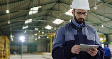 Kafkas erkek fabrika işçisi elinde bir tablet cihazla yürüyor. Manufactory alanı. İçeride. Portre