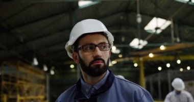 Erkek fabrika işçisi kask ve büyük bir fabrikada yürüyüş gözlük kapatın. İşlem arka plan üzerinde çalışıyor. Portre vurdu
