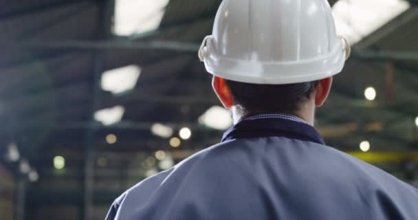 Close up do trabalhador da fábrica em um capacete e óculos andando em uma instalação industrial. Processo de trabalho em segundo plano. Traseira e de um lado — Vídeo de Stock