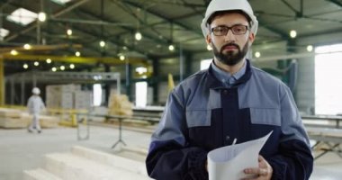 Fabrika işçisi portre çekim ına hemlet ve büyük mobilya fabrikası werehouse gazetelerde ile ayakta ve kameraya poz gözlük. Kapalı