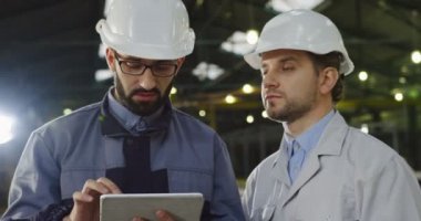 Fabrika odanın ortasında ayakta, bir tablet üzerinde kaydırma ve büyük bir sanayi tesisi çalışma alanı planlama yaparken de bir oda alanı göstererek kask iki mühendislerince. Portre vurdu. Kapat