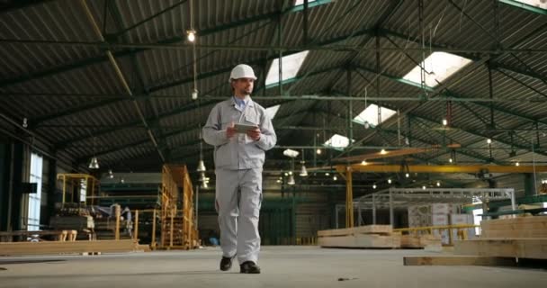 Manlig fabriksarbetare i en hamlet och särskilda enhetliga promenader genom möbler fabriken. Inomhus. Skott från nedan — Stockvideo