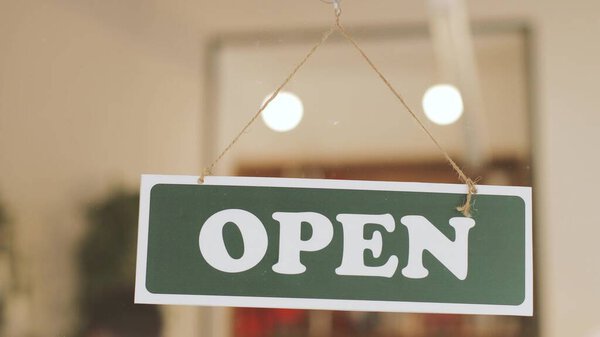 Portrait of young man turning over a "close" sign in his cafe window. Close up shot. the owner of cafe openning cafe.coronavirus COVID-19 pandemic of 2020.
