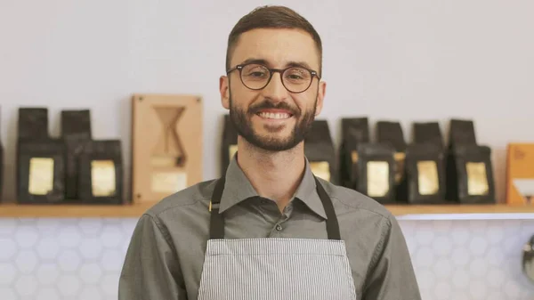Portret de aproape de barista hipster fericit de sex masculin la cafenea care posedă și zâmbesc pe camera de filmat. Imagine de stoc