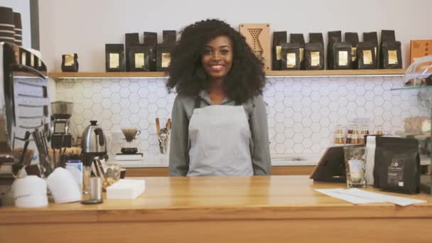 Πορτρέτο του γυναικείου αφροαμερικανού barista με καφέ σγουρά μαλλιά σταυρώνουν τα χέρια και χαμογελά στην κάμερα στο καφέ καφέ. Έννοια Αργή κίνηση — Αρχείο Βίντεο