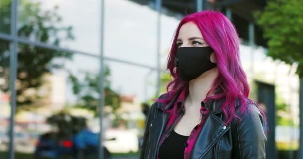 Caucasian extraordinary young girl with pink hair meeting friend at street and greeting with elbows gesture. Stylish female hipster in mask meet acquainted guy. Covid-19 pandemic time. — Stock Video