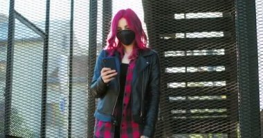 Beyaz, pembe saçlı, siyah deri ceketli beyaz bir bayan hippi merdivenlerde zımparalıyor ve akıllı telefondan mesaj yolluyor. Maskeli olağanüstü bir kız telefonda kayıyor, oynuyor.