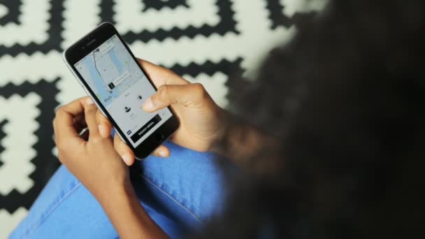 Nueva York - 10 de junio de 2017: uber app. Vea desde arriba a una mujer afroamericana usando Uber para reservar un taxi en el teléfono inteligente negro. Vertical. Fondo texturizado — Vídeo de stock