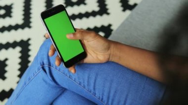 Siyah cep telefonunda dikey olarak siyah ekranlı Afro-Amerikan kadın elleri görünüyor. Krom anahtar. Desenli arkaplan