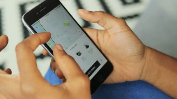Нью-Йорк - 10 июня 2017 года: приложение uber. Вид сверху афроамериканки, пользующейся uber и выбирающей такси и его маршрут на черном смартфоне. По вертикали. Текстурированный фон — стоковое видео