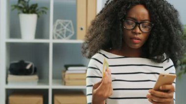 Çevrimiçi alışveriş ve kredi kartıyla alışveriş yapmayı başaran güzel kıvırcık saçlı Amerikalı genç bir kadın.