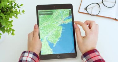 New York - 15 Mayıs 2020: Beyaz kadın harita uygulamasında siyah tablet cihazına tıklayarak kayıyor. Uygulamalı bilgisayar kullanan ve şehirde bir yer arayan bir kadın. Coğrafi konsept.