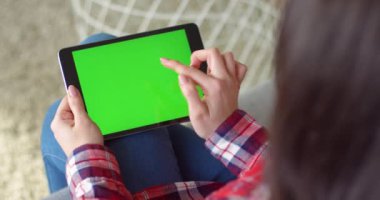 Kafkasyalı kadının elindeki siyah yatay tablet cihazına bak. Kadının elinde yeşil ekranlı bir bilgisayar var. Krom anahtar. Uygulama konseptinde tıklama, yakınlaştırma, kaydırma.
