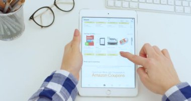 New York - 15 Mayıs 2020: beyaz tablet beyaz kadın ellerinde. Masadaki çevrimiçi mağaza uygulamasında ürünleri seçerken kadın kaydırma ve tıklama ekranında. Uygulamada alışveriş ögeleri