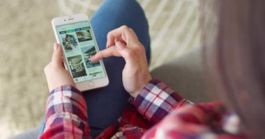 New York - 15 Mayıs 2020: beyaz akıllı telefonun üzerinden beyaz bir kadının ellerine bakın. Ev fotoğrafları içeren Pinterest uygulaması. Kadın telefon dinlemesi ve kaydırma yapıyor. Ev tasarımı kavramı.