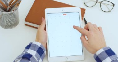 New York - 15 Mayıs 2020: beyaz tablet beyaz beyaz kadının ellerinde. Kadın Takvim uygulaması açıyor ve bilgisayarda kayıyor. Başvuruda tarih ve gün aranıyor. Planlama kavramı.