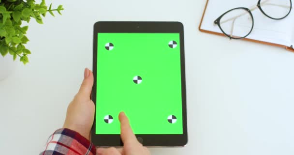 Dispositivo tablet preto com tela verde em mãos de mulher caucasiana. Rolagem feminina, zoom e tocando na tela de tecla chroma do computador vertical com movimento de rastreamento na mesa branca. Navegação on-line . — Vídeo de Stock
