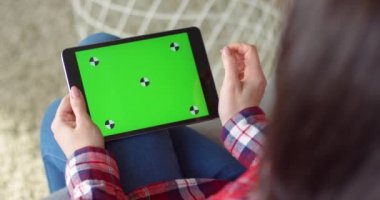 Kafkasyalı kadının elindeki siyah yatay tablet cihazına bak. Kadının elinde yeşil ekranlı bir bilgisayar var. Krom anahtar. Tıklama, yakınlaşma, takip hareketleriyle kaydırma.