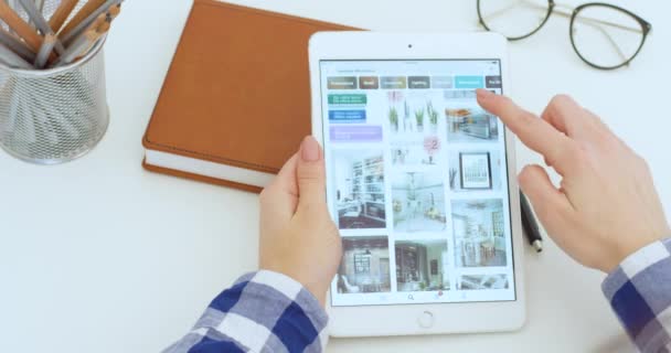 Νέα Υόρκη - 15 Μαΐου 2020: Λευκή συσκευή tablet στα χέρια Καυκάσιας γυναίκας που χρησιμοποιεί την εφαρμογή Pinterest και κοιτάζει φωτογραφίες διακόσμησης γραφείου. Γυναικεία υποκλοπή και κύλιση στον υπολογιστή. Έννοια σχεδιασμού. — Αρχείο Βίντεο