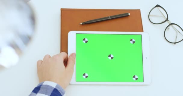 백인 여성의 손에 녹색 화면을 쥐고 있는 화이트 태블릿 장치. 여성들은 책상에서 움직임을 추적하는 수평 컴퓨터의 크롬 키 스크린을 스크롤하고 확대하고 두드리고 있습니다. 온라인 검색. — 비디오