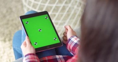 Kafkasyalı kadının elindeki siyah tablet cihazını omzunun üstünden izle. Kadının elinde yeşil ekranlı bir bilgisayar var. Krom anahtar. Tıklama, yakınlaşma, takip hareketleriyle kaydırma.