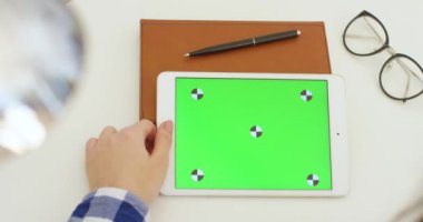 Beyaz tablet cihazı. Beyaz kadının ellerinde yeşil perde var. Kadın kaydırma, yakınlaştırma ve masadaki izleme hareketi ile yatay bilgisayarın krom anahtar ekranına tıklama. Çevrimiçi tarama.