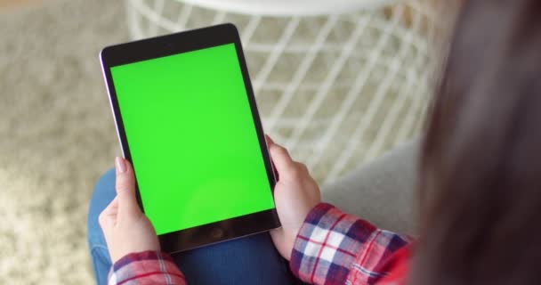 View over shoulder on black vertical tablet device in hands of Caucasian woman. Female holding computer with green screen and watcing video. Chroma key. — Stock Video