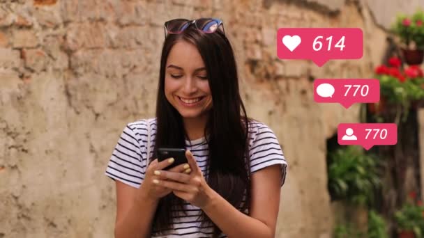 Hermosa joven mujer caucásica sonriendo al recibir gustos de corazones, comentarios y nuevos seguidores en las redes sociales. Chica al aire libre golpeando en el teléfono inteligente. blogger contando reacciones por teléfono . — Vídeos de Stock