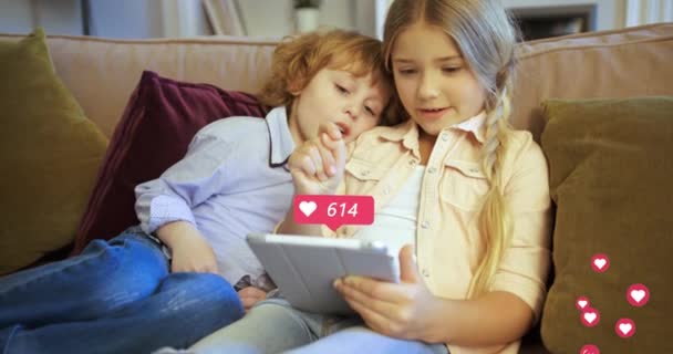 Kaukasische Kinder, Jungen und Mädchen, die zu Hause auf dem Sofa sitzen und Tablet-Geräte benutzen. Herzen zählen in den sozialen Medien. Kleine Kinder, Schwester und Bruder auf der Couch, die am Computer spielen. Reaktionen im Internet. — Stockvideo